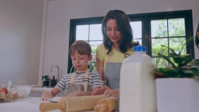 Woman and child baking in kitchen, rolling pin shaping dough with milk nearby as family cooking activity, mother and child preparing homemade food together in bright family home setting