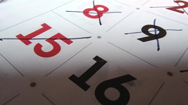 Close up view of person marking off dates on paper calendar with pen, time management and scheduling concept