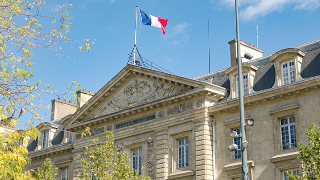 French flag waving above historic Caserne Aliene building facade in Paris