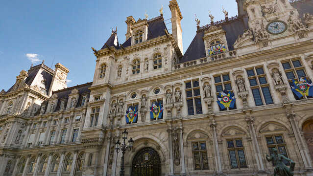 Hotel de Ville facade featuring historical architecture, statues, and flags under sunlight