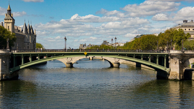 Pont au Change bridge spans the Seine River with Conciergerie in the background under a blue sky