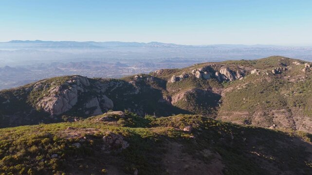 Epic golden hour aerial over hiking trails near Sandstone Peak in the Santa Monica Mountains, withlush rolling hills, boulders and views of the Simi and Conejo valleys in the distance.