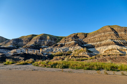 Hoodoos and layered badlands under a clear blue sky at sunrise,  Drumheller, AB TOJ OYO , Alberta, Canada