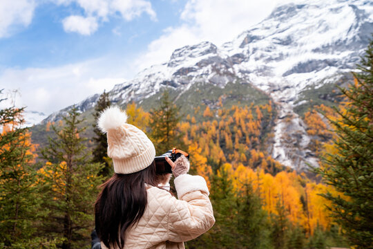 Young female tourist relaxing and enjoying at beautiful autumn scenery landscape at Mount Siguniang national park in Sichuan, China