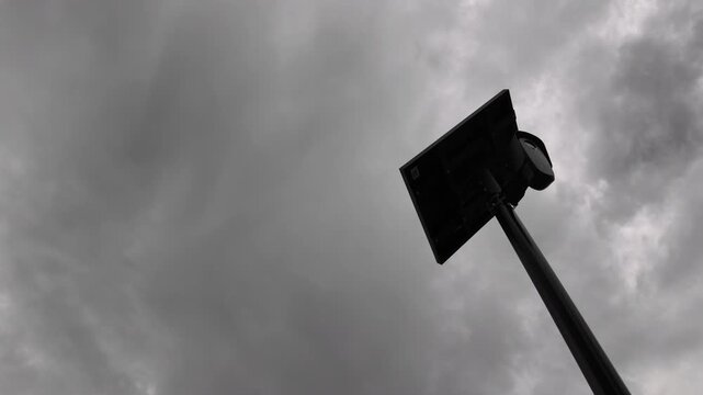 Ominous storm cloudy view of an AI artificial intelligence camera and solar panel on a pole.