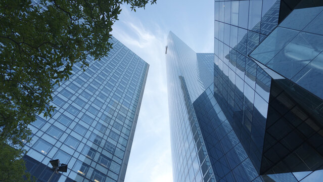 PARIS, FRANCE - SEPTEMBER 1, 2026 - Modern glass skyscrapers and tree foliage framing the vibrant business district sky