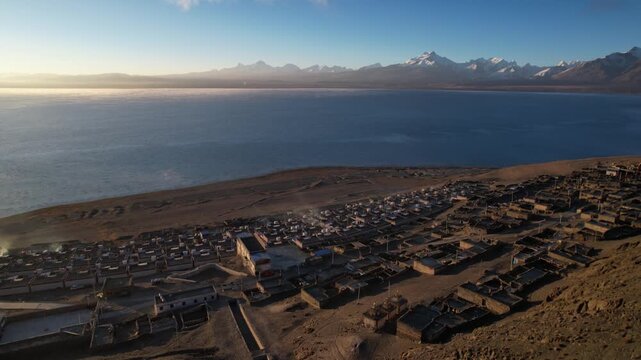 Aerial drone flight over Peiku Tso lake and Lapu village with Shishapangma mountain in Tibet
