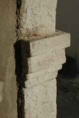 A close up shot shows a rough textured stone corbel integrated into an ancient wall structure catching warm sunlight. © nahhan