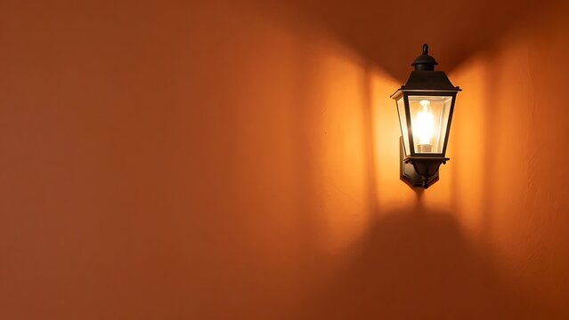 Vintage wall lantern illuminating warm light casting shadow on textured orange-brown wall architectural lighting design