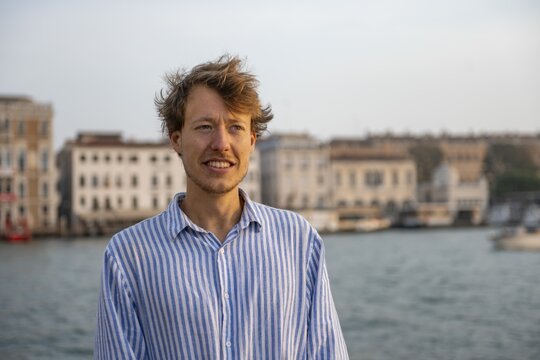 Young man in striped shirt, portrait, on the banks of the Grand Canal, behind Campanile, Venice, Veneto, Italy