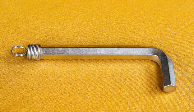 Silver hexagonal L-shaped key made of high-strength chrome vanadium alloy steel on a gold cloth background.