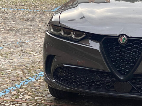 Detailed view of the front fascia of a modern Alfa Romeo automobile parked on a cobblestone street