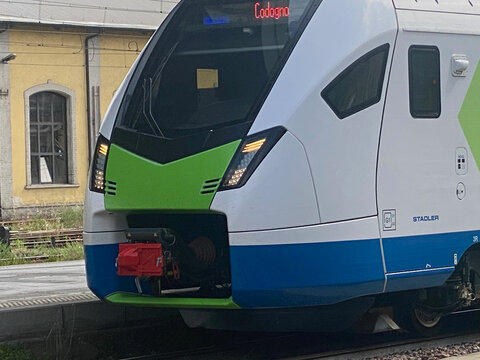 Close-up view of the front of a contemporary Stadler train featuring a vibrant green and blue color scheme, ready for departure
