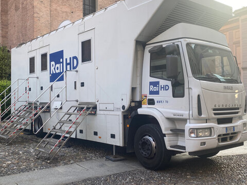 A mobile television studio truck with RAI HD logo and access stairs parked on a cobblestone street