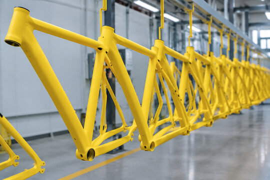 A row of bicycle frames coated in a vibrant matte yellow powder.