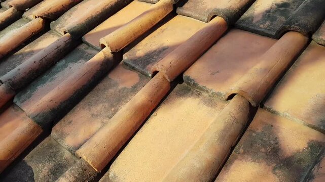 Moving shadows across weathered clay roof tiles with static camera