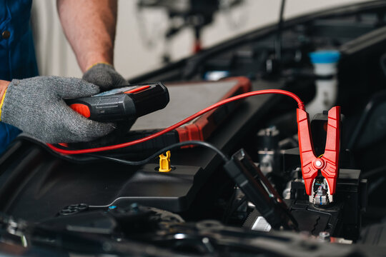 Ev car battery cells service Car battery jump starter electrical testing mechanic automotive repair vehicle maintenance red cable battery terminal engine compartment workshop setting