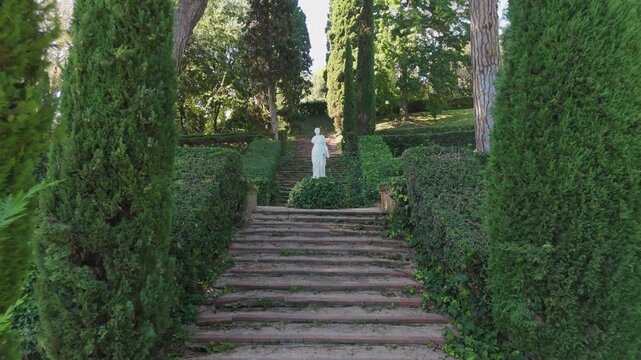 Steps on the shady alleys of Santa Clotilde Park in Lloret de Mar, Costa Brava, Spain - paths among green trees and bushes, statues