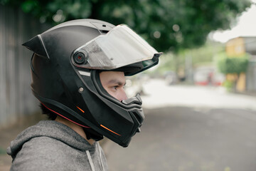Side profile portrait of man wearing motorcycle helmet on street. Close up of motorcyclist helmet visor raised in profile view © YanlethRivera