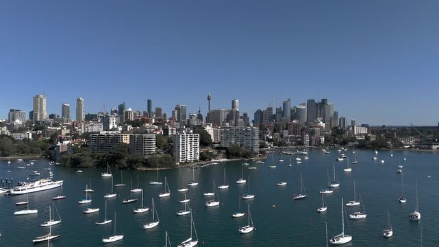 Sydney skyline from aerial view on beautiful sunny day. Camera tracks across Rushcutters Bay looking across to Elizabeth Bay, the CBD and Garden Island. Yachts and Motor Boats are on moorings.