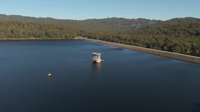 Wide aerial shot revealing the silvan reservoir, its dam, and the surrounding forested hills