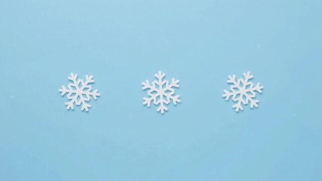 Three white decorative snowflakes on a light blue background, top view. Winter, Christmas, and festive holiday season concept.