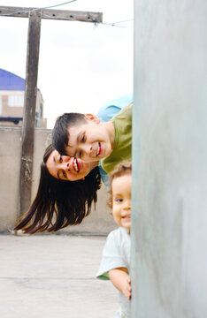 Three happy kids peeking behind the wall.