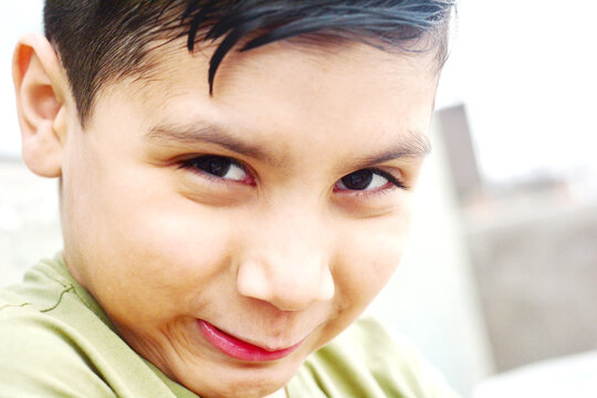 Funny boy with a weird smile expressing disgust or sneaky plan.