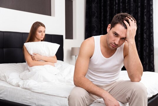 Stressed couple sitting on bed after an argument in the bedroom