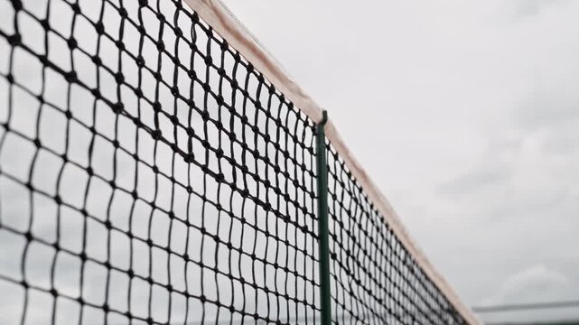 Yellow tennis ball hitting net in low angle slow motion during match on outdoor court. Clip suits sports commercials, athletic coaching videos, tournament promotions