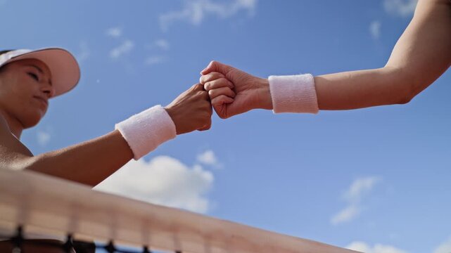 Young adult Biracial woman and opponent fist bumping over net after match in slow motion. Footage suits sports marketing, teamwork campaigns, athletic branding, and tournament advertising