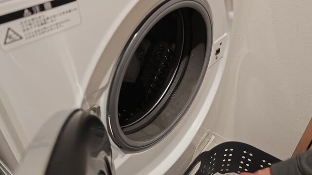 ドラム式洗濯機にタオルを入れる女性の手元　スローモーション