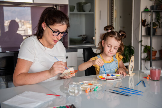Mother and daughter paint Halloween decorations at home