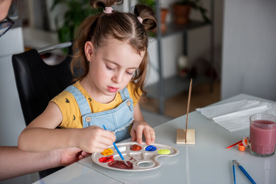 Young girl painting with watercolor at home table