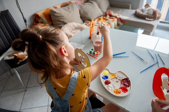 Girl make Halloween decoration at home with paint