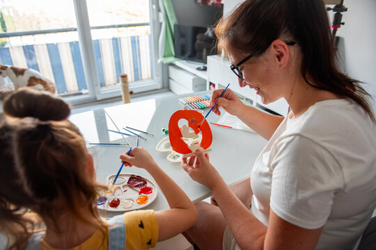 Mother and daughter paint Halloween decorations at home