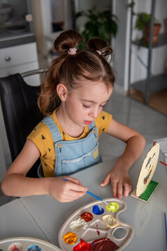 Young girl paint Halloween decoration with her mother