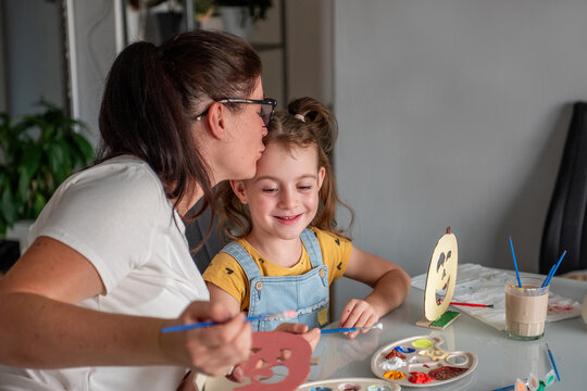 Mother kiss daughter  while creating Halloween decorations at home