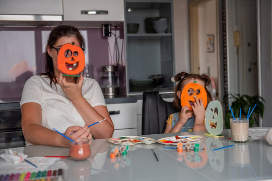 Mother and daughter play with diy pumpkin masks at home