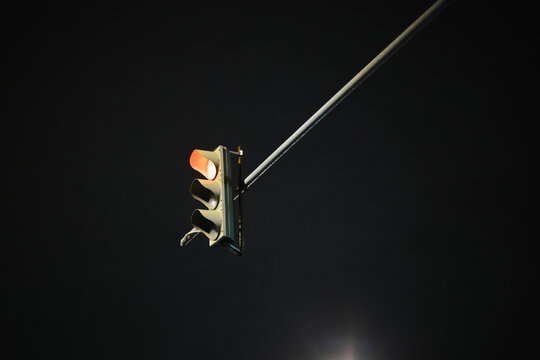 Suspended traffic signal glowing against dark night sky