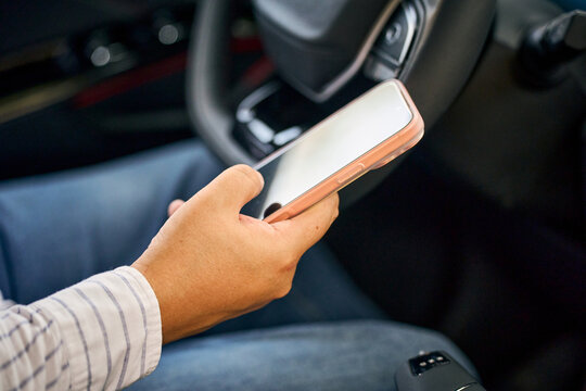 Driver holding smartphone inside car for mobile connection