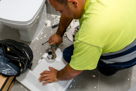 Plumber remove old wall-mounted sink during bathroom renovation