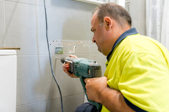 Plumber drill tiled bathroom wall for new vanity installation