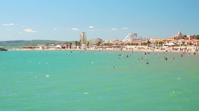Families and friends swim and relax by the water. Valras, France .