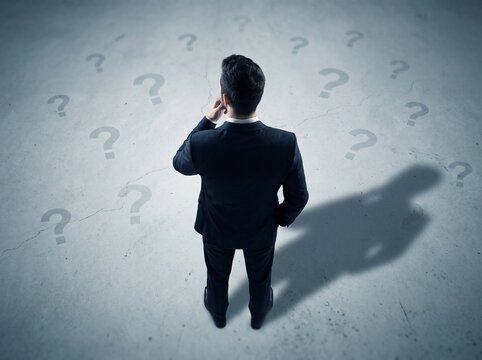 Businessman contemplating surrounded by question marks, representing uncertainty, decision making, problem solving, and searching for answers.