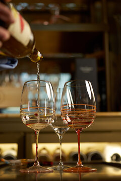 Sommelier Pouring White Wine into Decorated Glasses in Restaurant