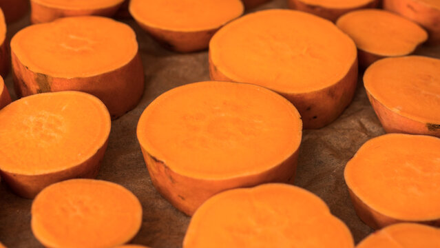 Raw Sweet Potato Slices Ipomoea batatas Arranged on Baking Paper Ready for Roasting &mdash; Concept: Healthy Plant Based Cooking, Meal Preparation Flat Lay, Vibrant Food Background