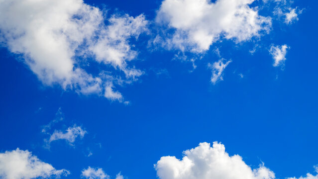 small white clouds in an open blue space of sky