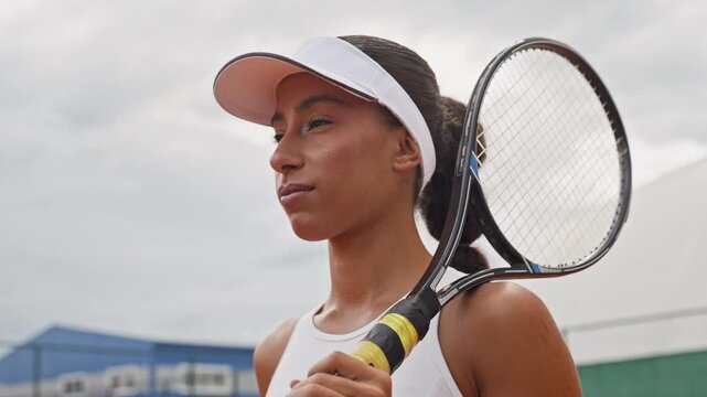 Biracial female tennis player holding racket on shoulder in slow motion. Clip works well for athletic apparel advertising, sports training and fitness promotions