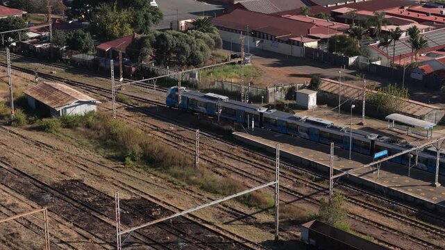 Aerial view of a passenger train travelling along railway tracks through a densely built industrial area